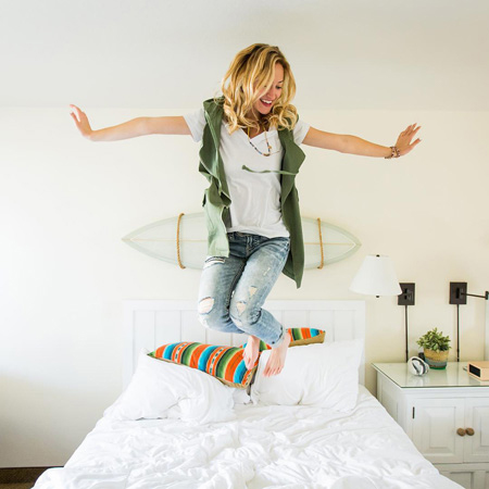 Happy woman jumping on a bed at Laguna Beach House